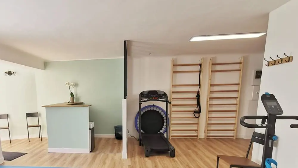 Un cabinet de kinésithérapeute avec une banque d'accueil, un tapis de course et un vélo d'appartement